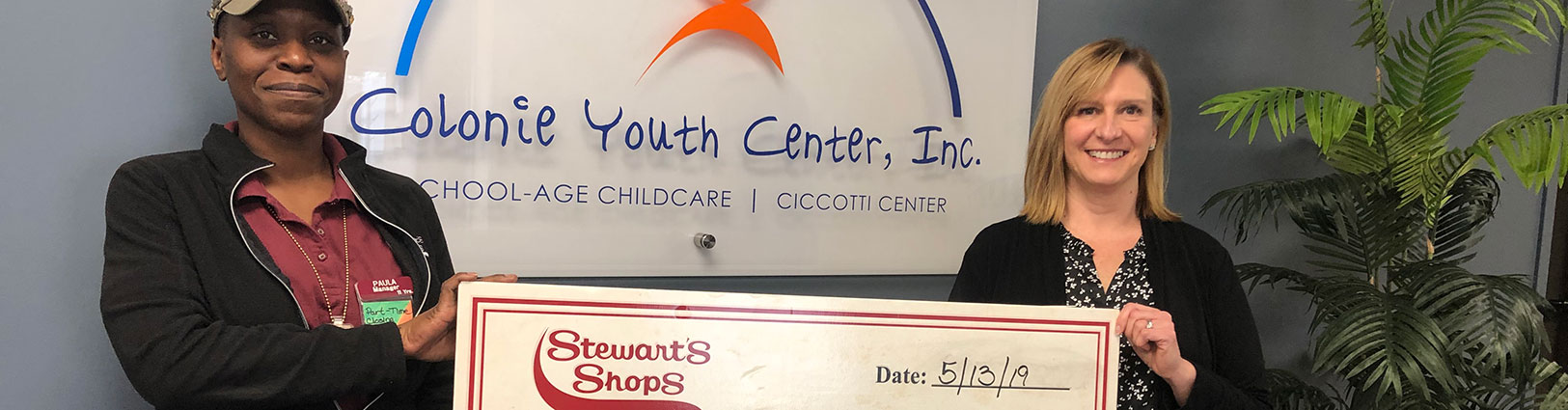Women hold an oversized donation check from Stewart's Shops to Colonie Youth Center